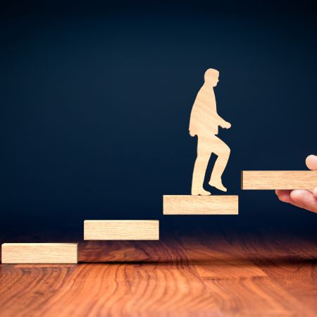 階段を一段ずつ上る人物のシルエットを表す木製オブジェの写真