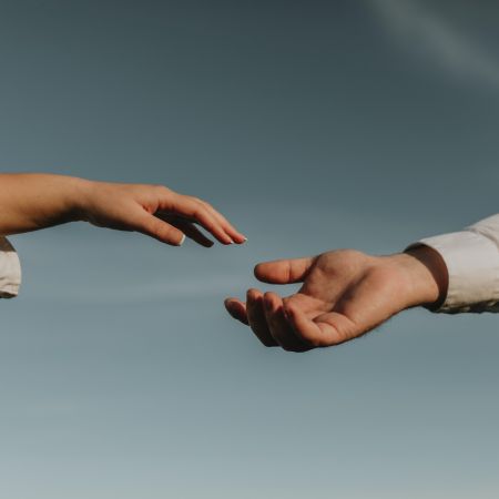 互いに手を伸ばし合い、つながりや支援を象徴する手の写真
